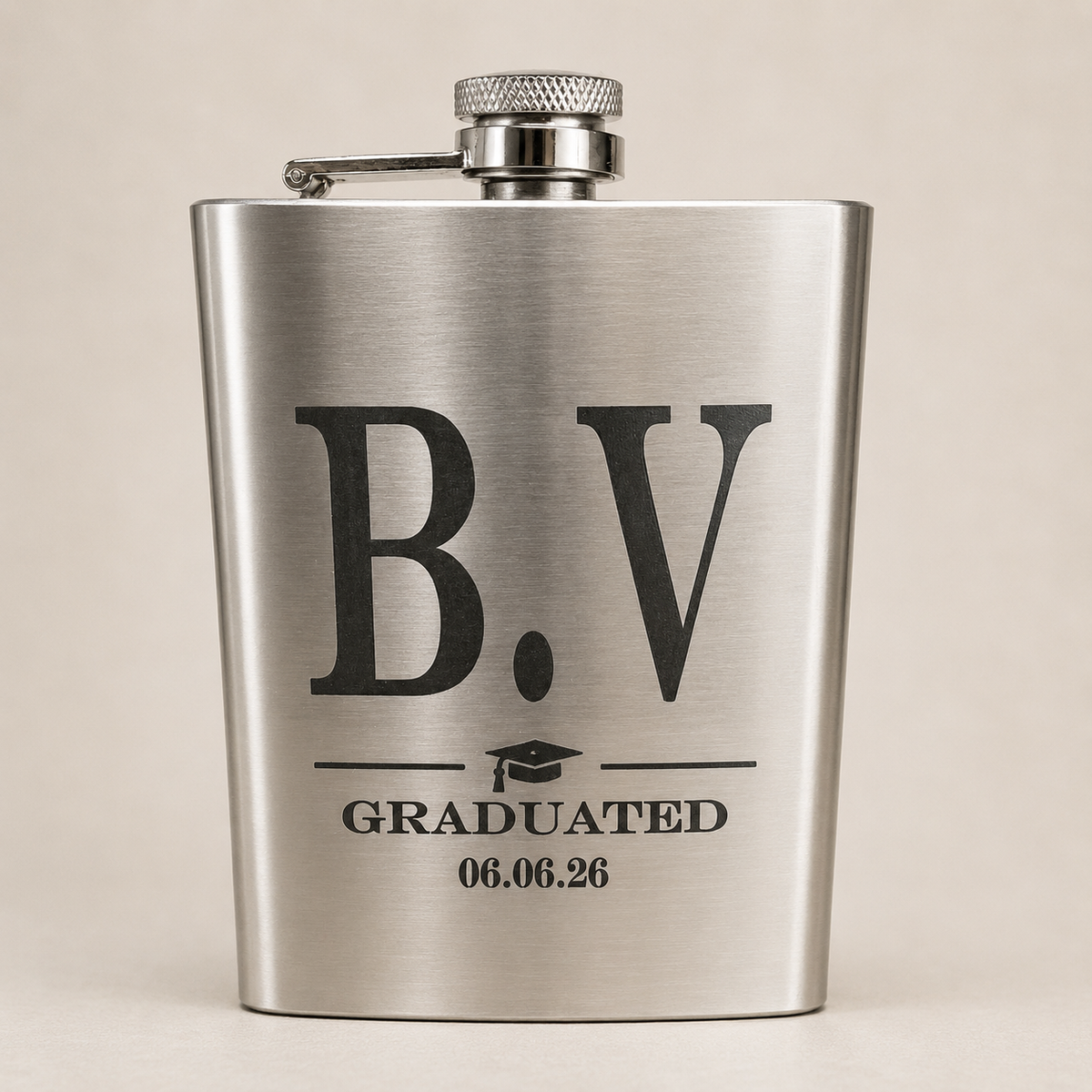 A brushed stainless steel flask with a personalized graduation design featuring the letters 'B.V', a graduation cap icon, and the text 'GRADUATED 06.